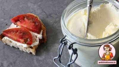یک ظرف شیشه ای پنیر ماسکاورپونه کنار نان تست و گوجه و پنیر ماسکارپونه